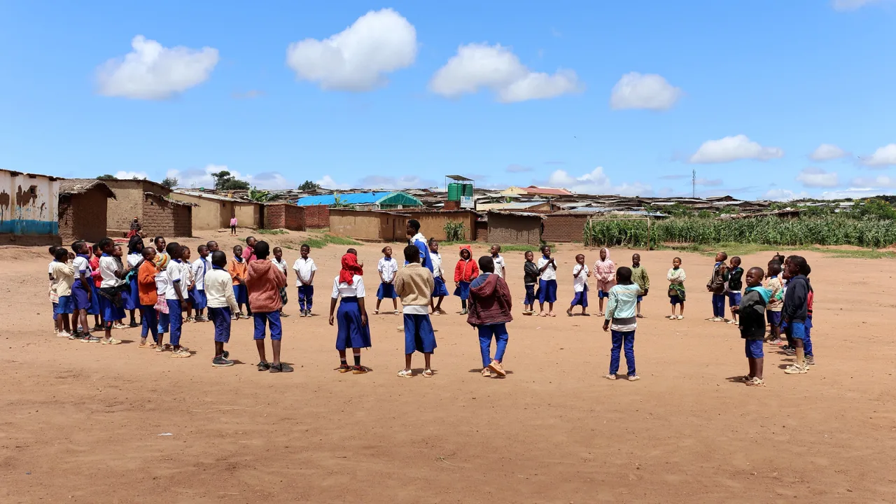 Students and teachers gathered in a circle activity during the Malawi pilot
